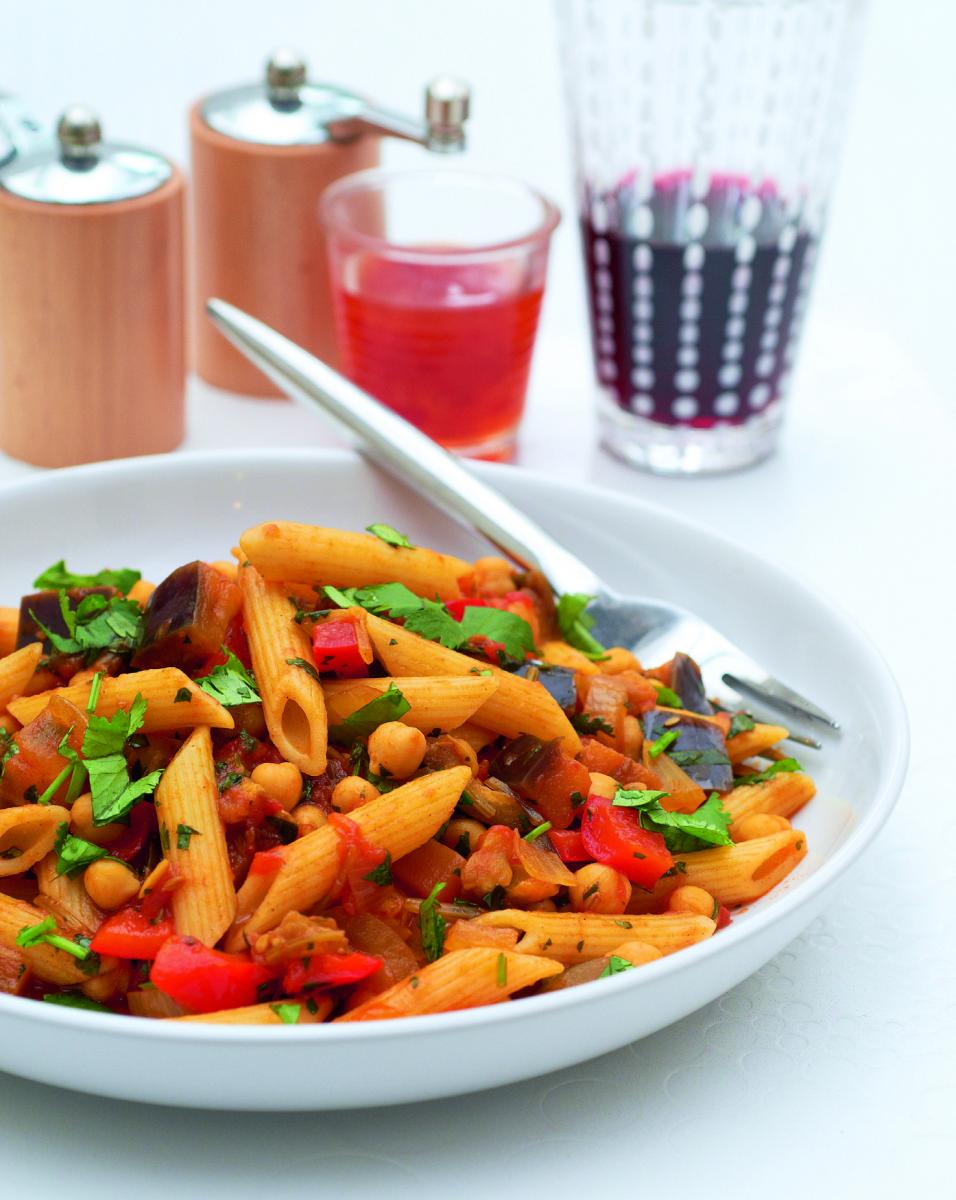 A shallow bowl of penne paste with aubergine and chickpeas.