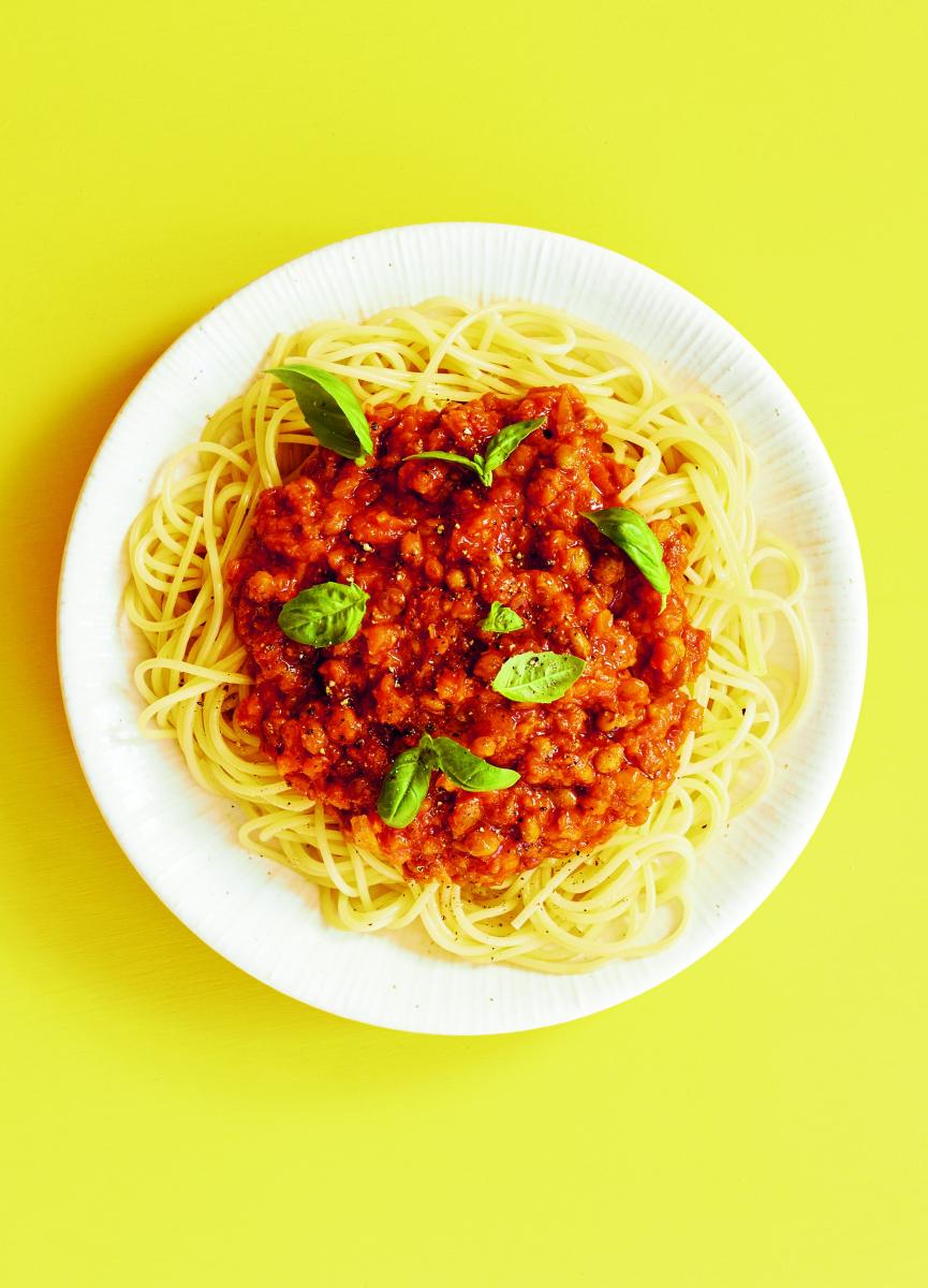 photograph of lentil ragu on a plate against a yellow background