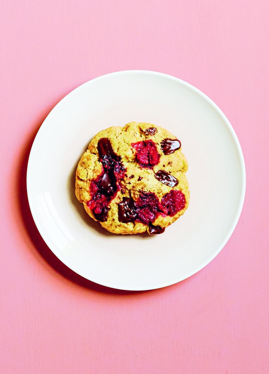 photograph of raspberry and chocolate microwave cookie on a plate against a pink background