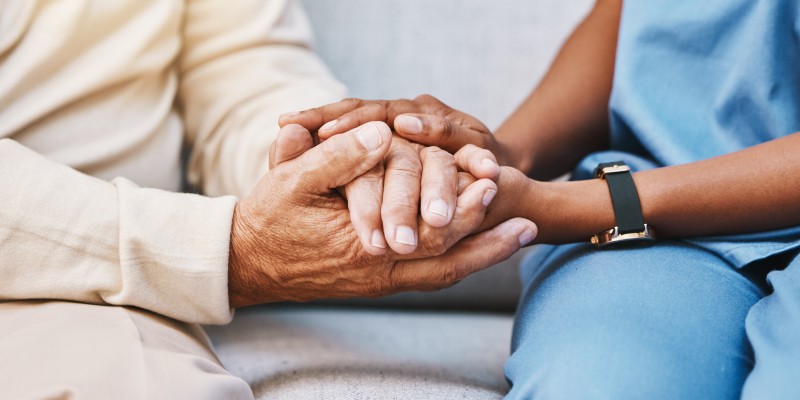 Nurse holding hands with elderly person