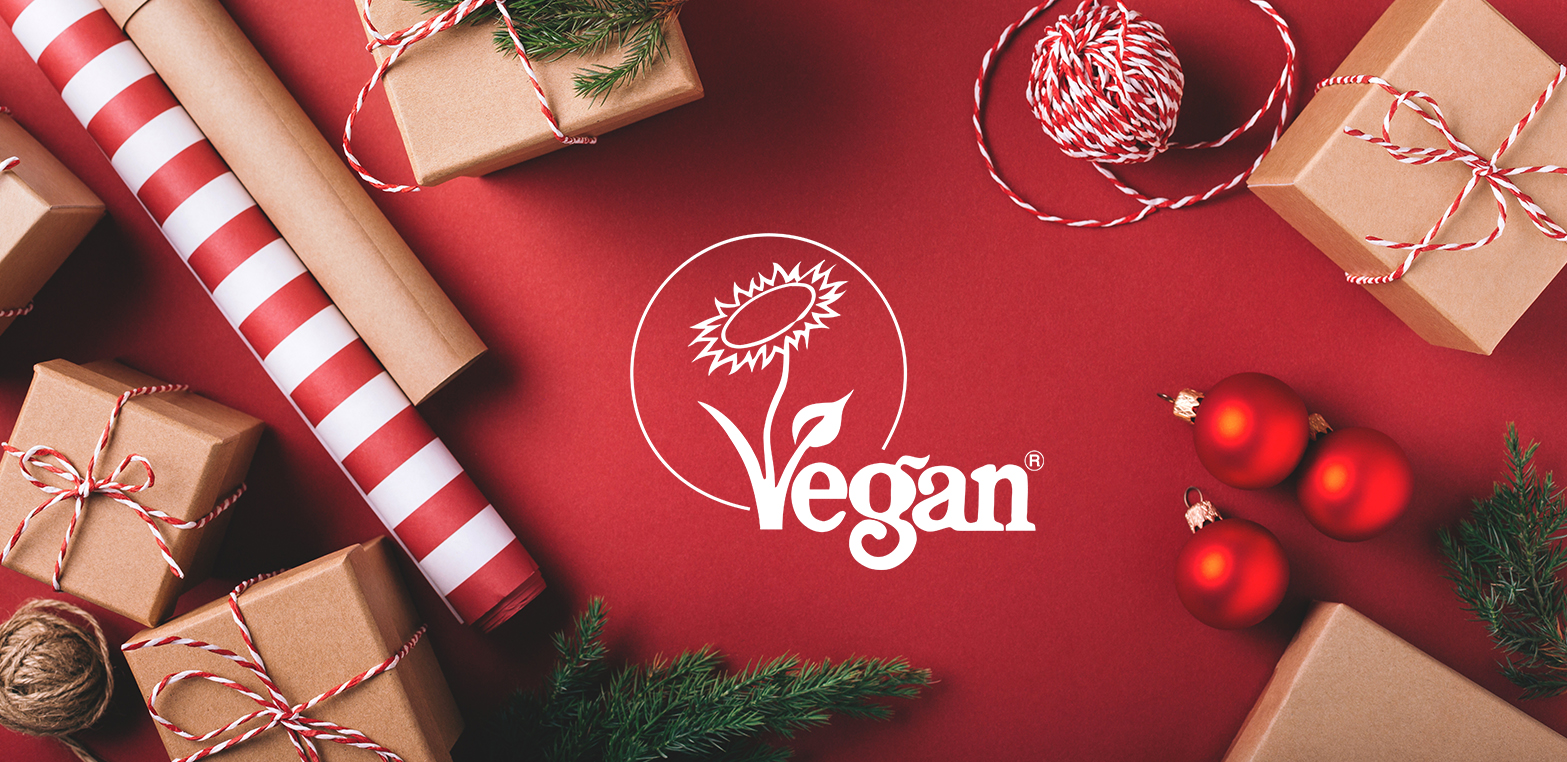 Boxed gifts and wrapping paper against a red background with the Vegan Trademark logo at the centre