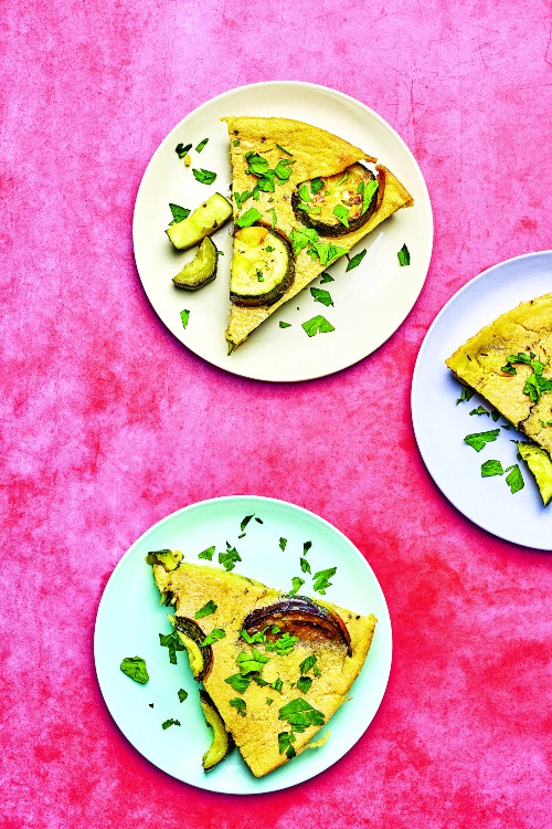 photograph of courgette and aubergine farinata on a plate against a pink bakground