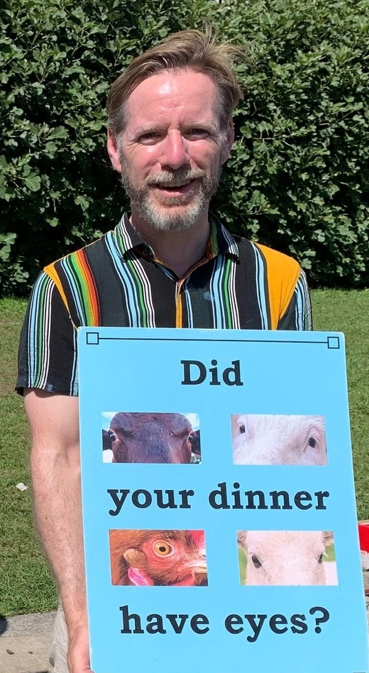 Vegan Society Treasurer holding sign saying 'Did your dinner have eyes?' sign