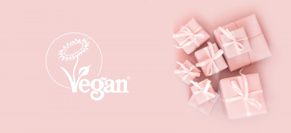 Pink gift boxes against a pink background with the Vegan Trademark sunflower logo on white