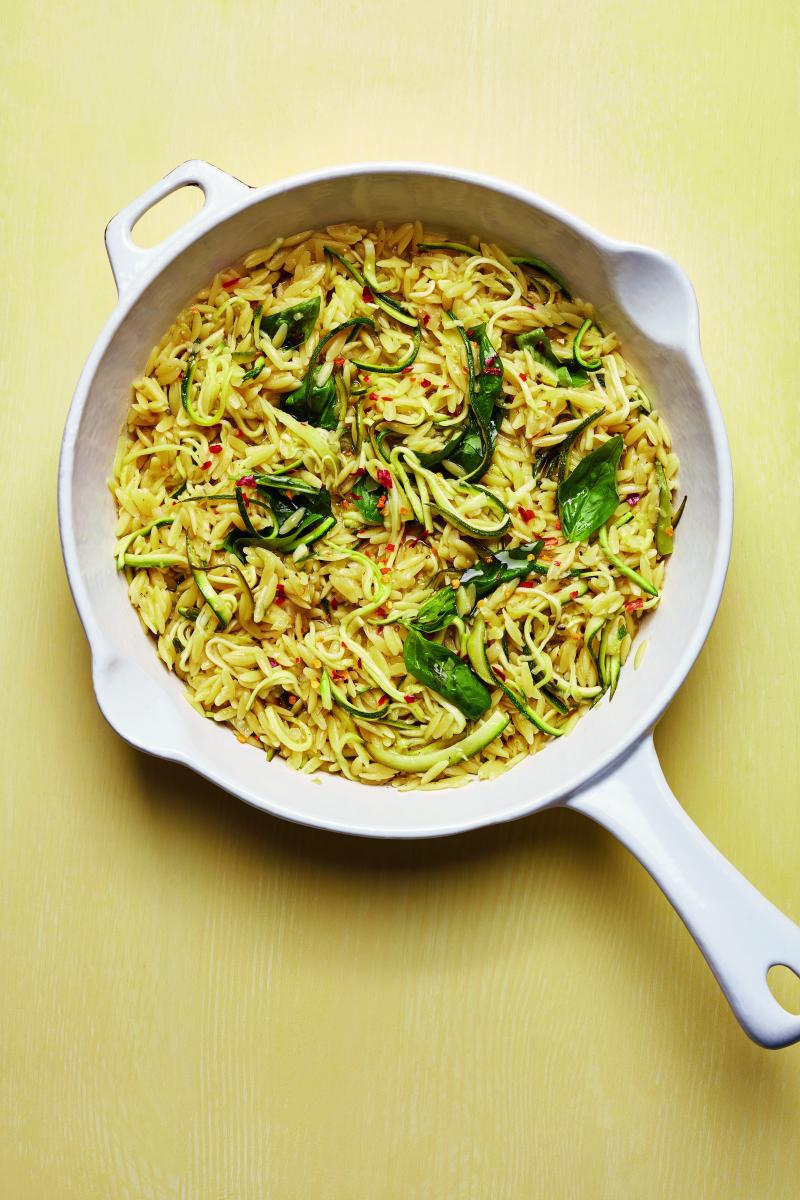 photograph of lemony courgette orzo in a pan against a yellow background