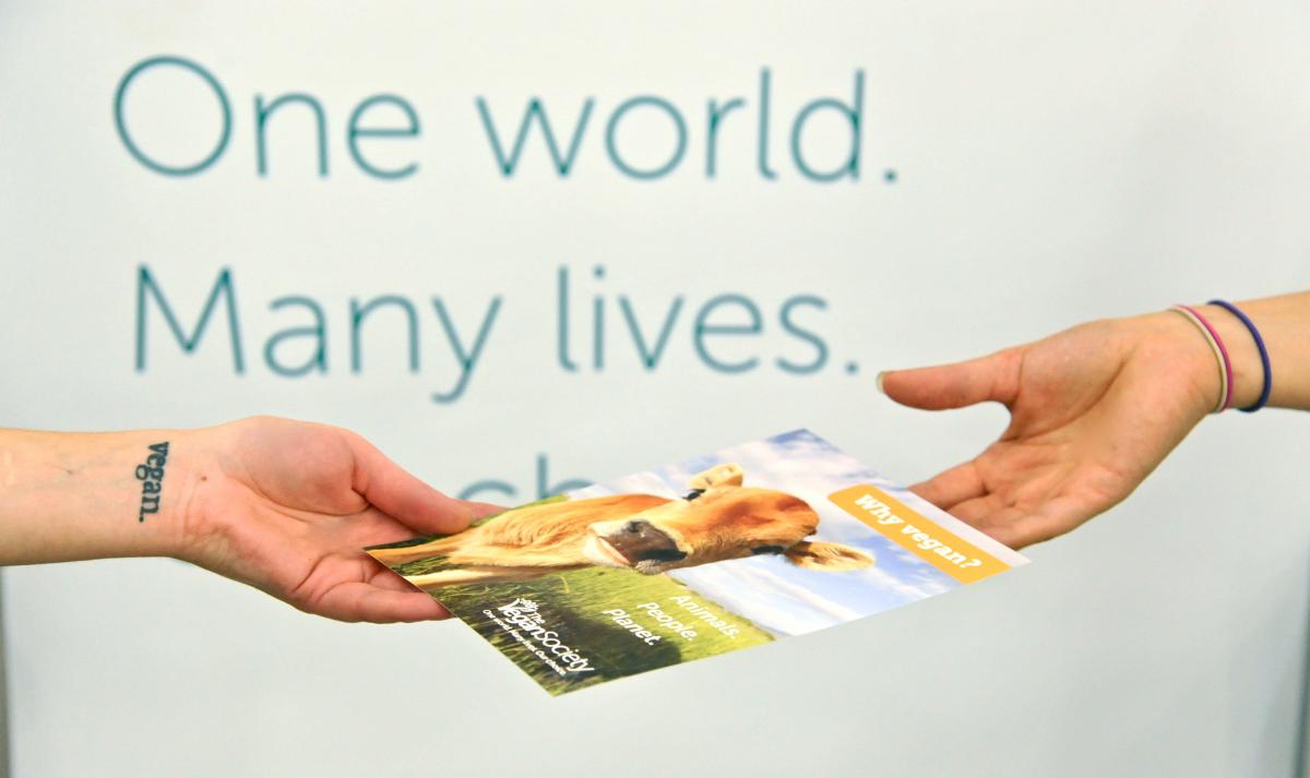 Hands exchanging a Vegan Society leaflet