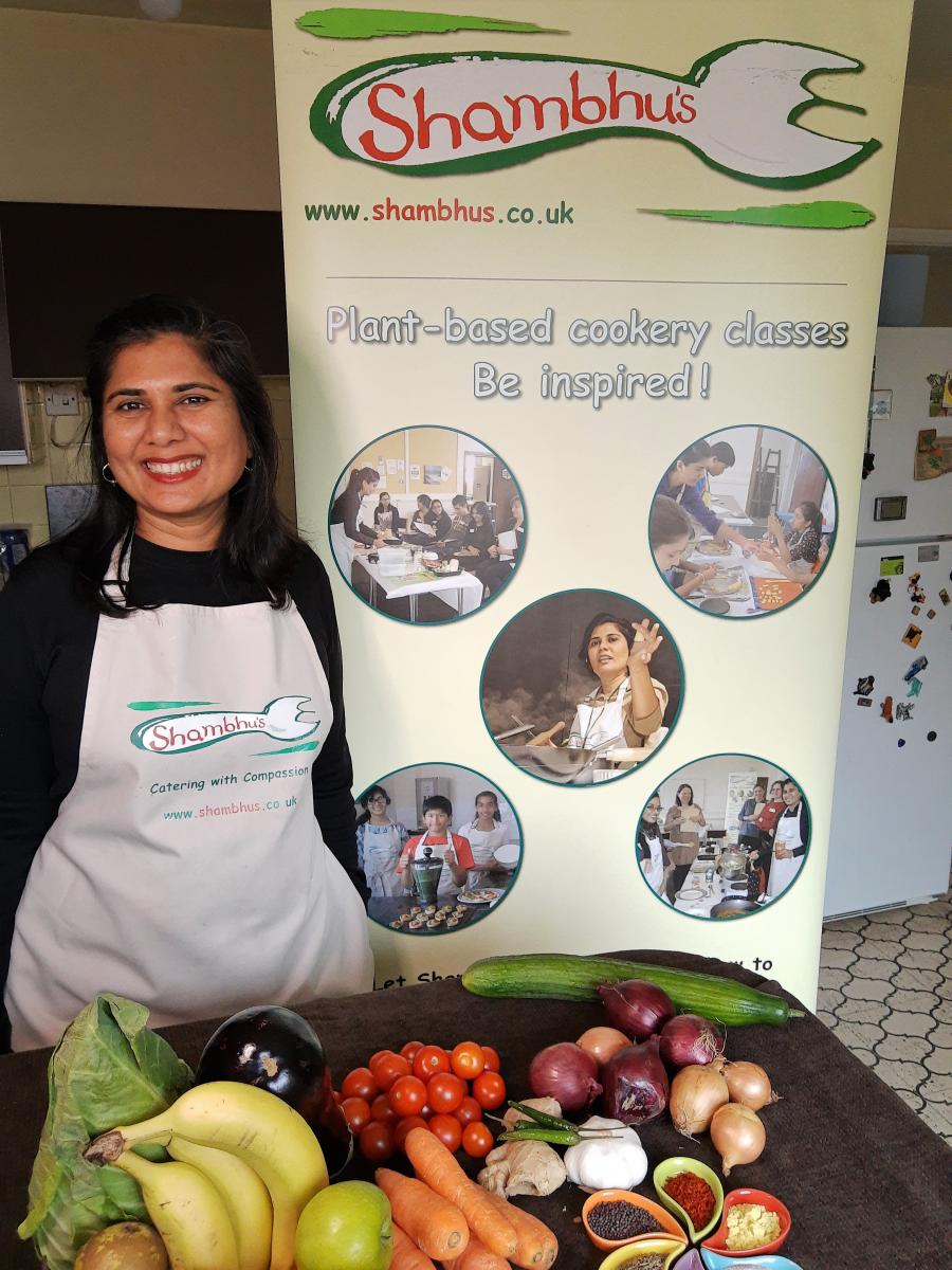 Lady at Shambhu's stand with fruit and veg on a table