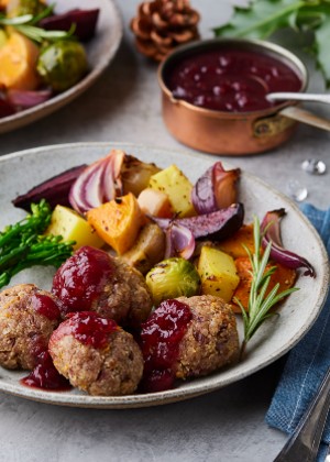 nut patties with orange sauce served on a plate surrounded by pine cones and holly