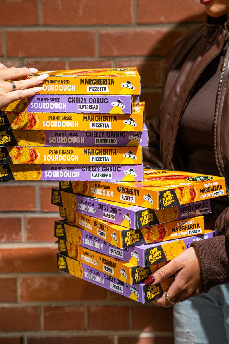 Person holding One Planet Pizza boxes