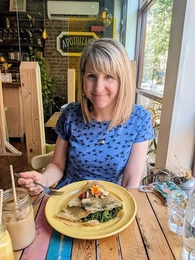 Image shows Rebecca, the creator of the Veggies Abroad Blog. She is white woman with blonde bob-length hair and is wearing a blue top. 