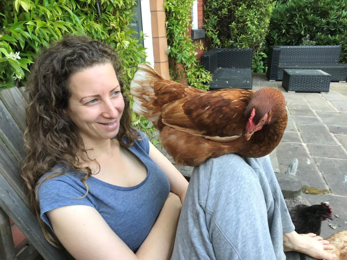 Charlotte with rescue chicken on their knee