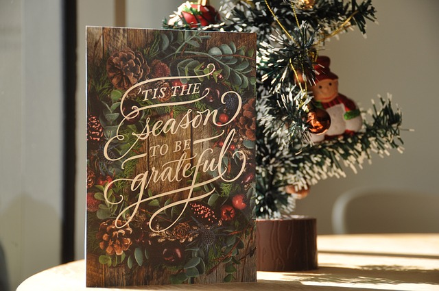 A Christmas card on a table with a miniature Christmas tree behind