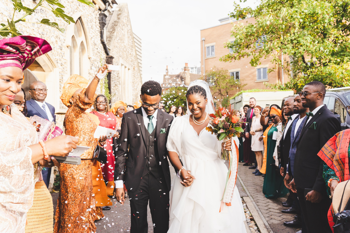 Tomi and her husband having confetti thrown on them by family 