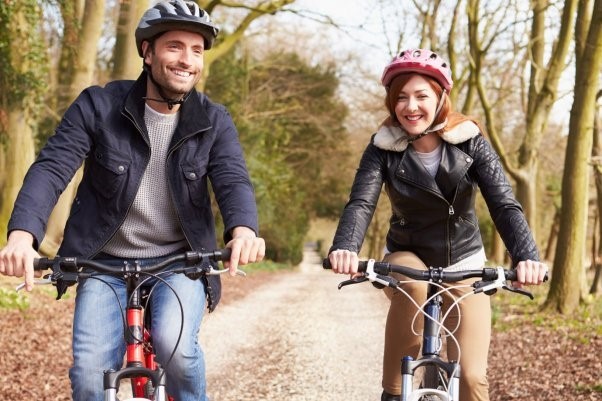 Two people smiling while cycling through the woods together