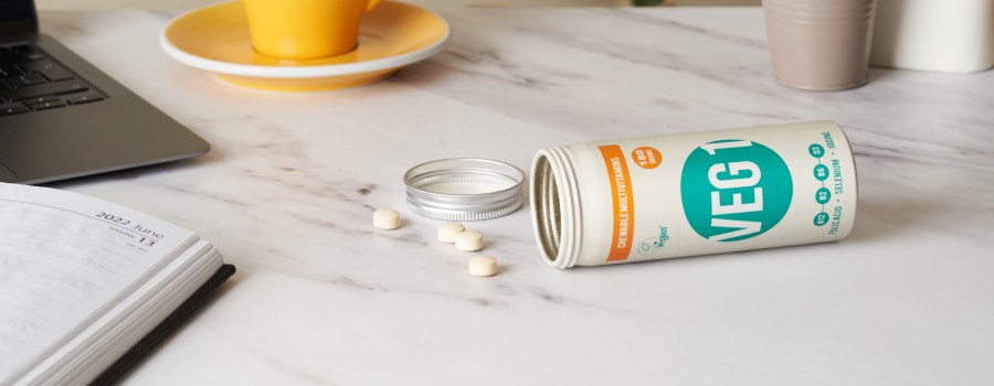 photograph of pot of VEG 1 on a table with supplements next to a mug and plant