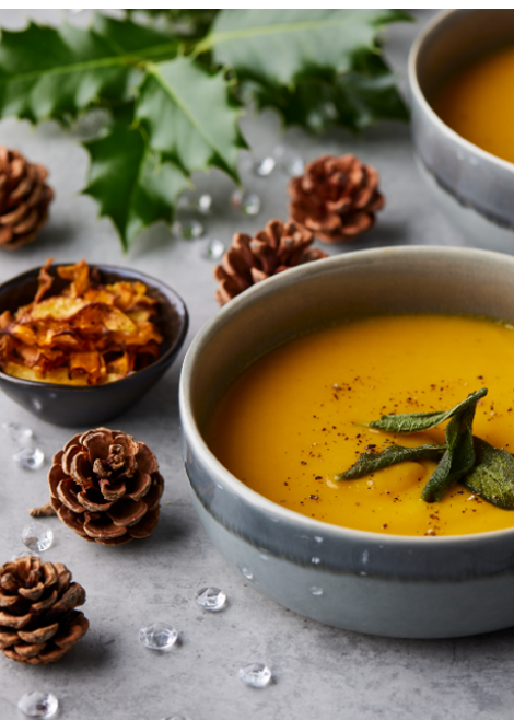 carrot soup with vegetable crisps surrounded by pine cones and holly