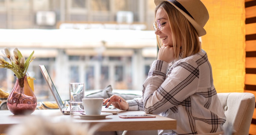 Person in cafe smiling at their laptop