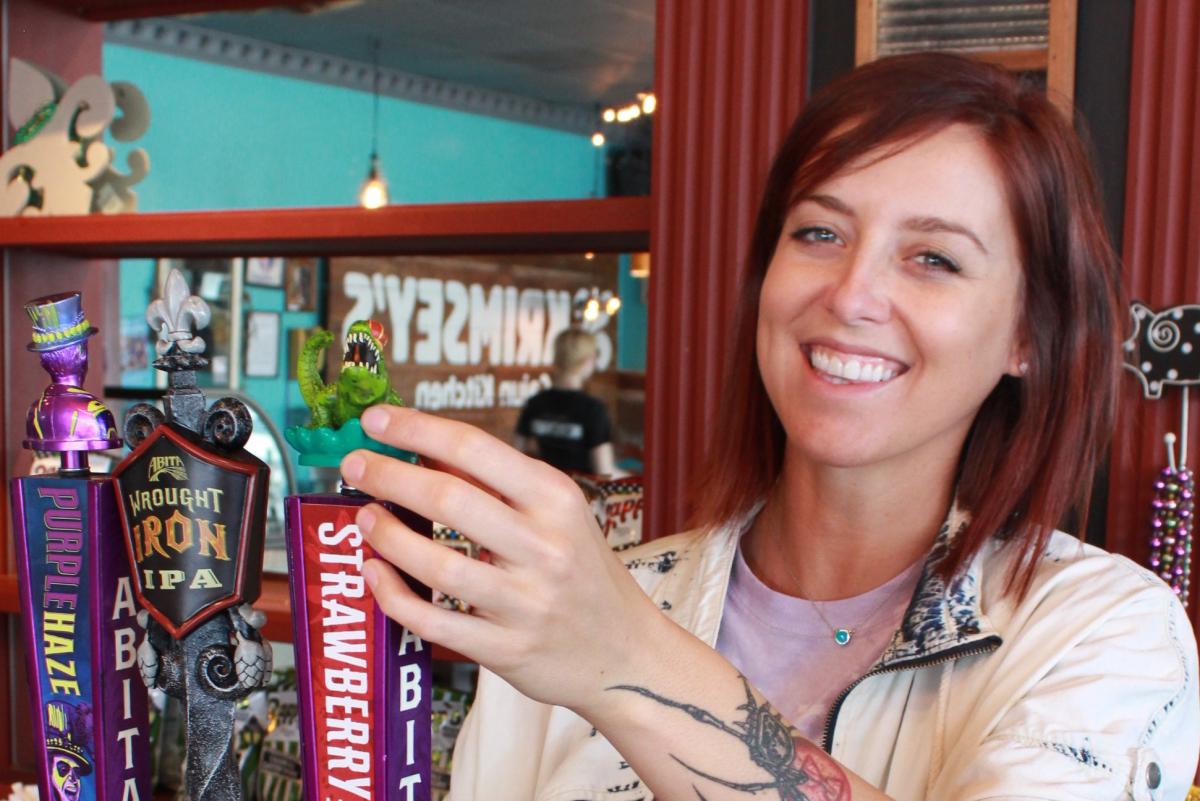 Krimsey at Krimsey's Cajun Kitchen at bar with hand on beer tap smiling