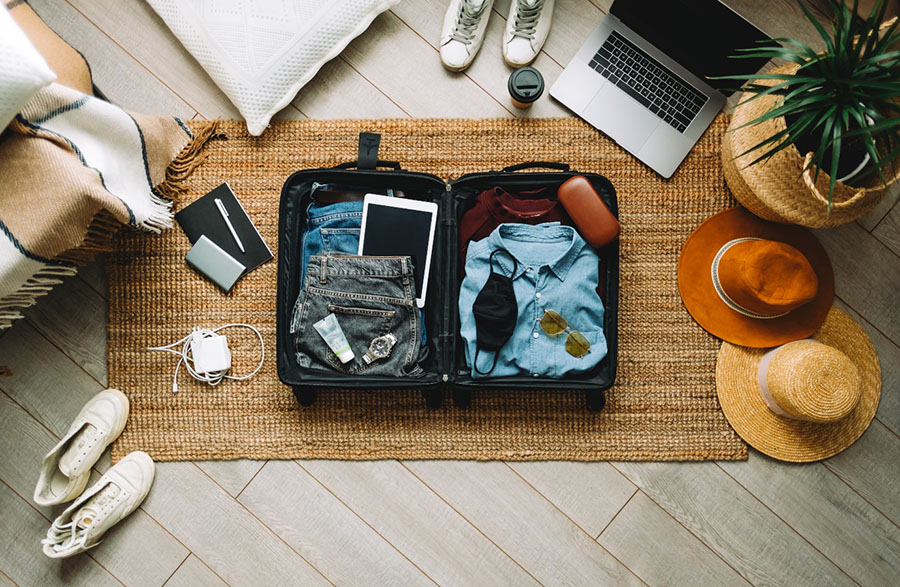 An open suitcase filled with clothes and resting on the floor