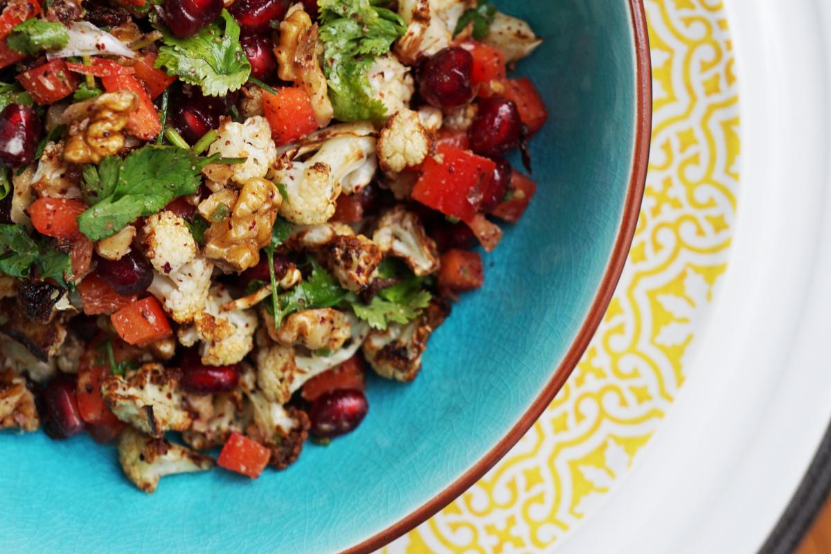 Vegan cauliflower sumac salad with pomegranate seeds, walnuts and red peppers served in a bowl