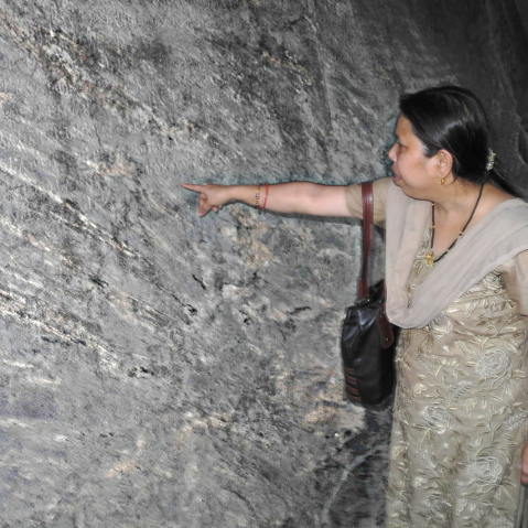 Image of Dr Bharati Pal pointing at the word "Dharma" on Ashoka's Dhauli rock edict, in eastern India