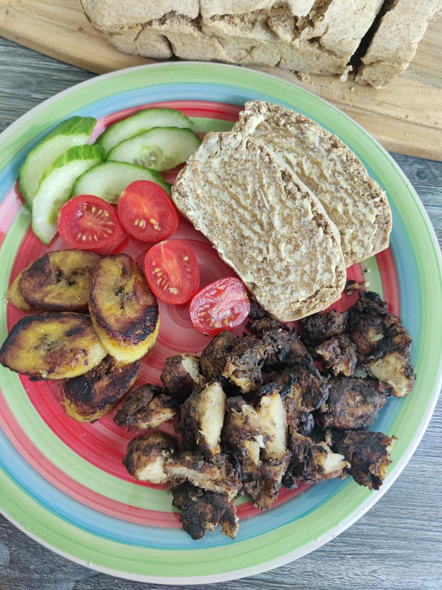 Photograph of jerk chickin and hard dough bread on a plate