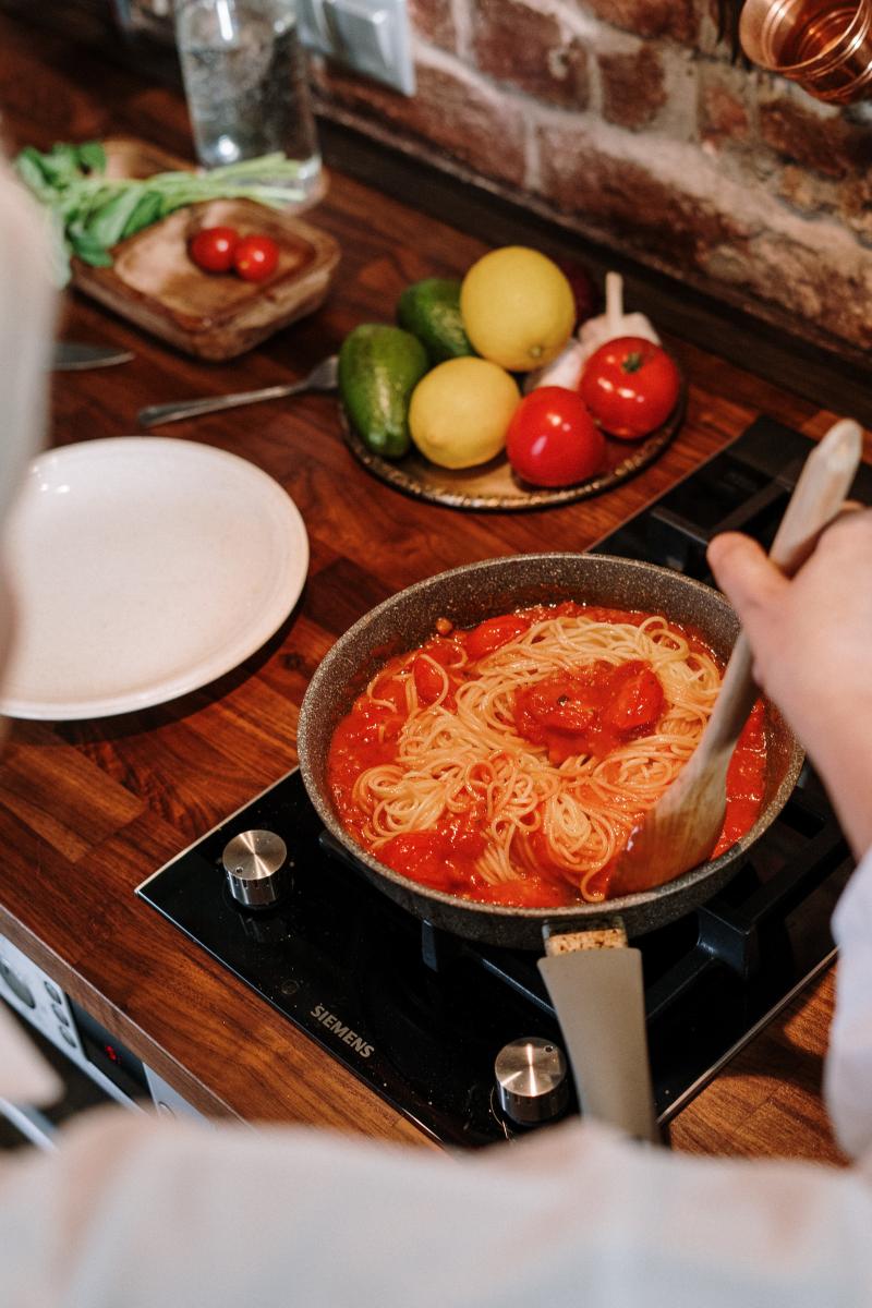 tomato sauce and spaghetti in a pan being stirred