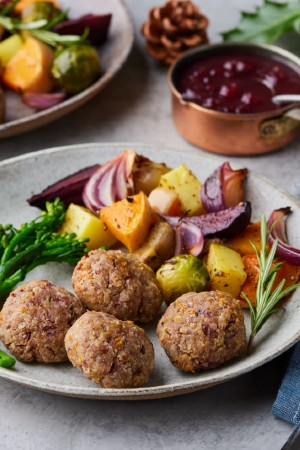 roasted mixed vegetables on a plate surrounded by pine cones and holly