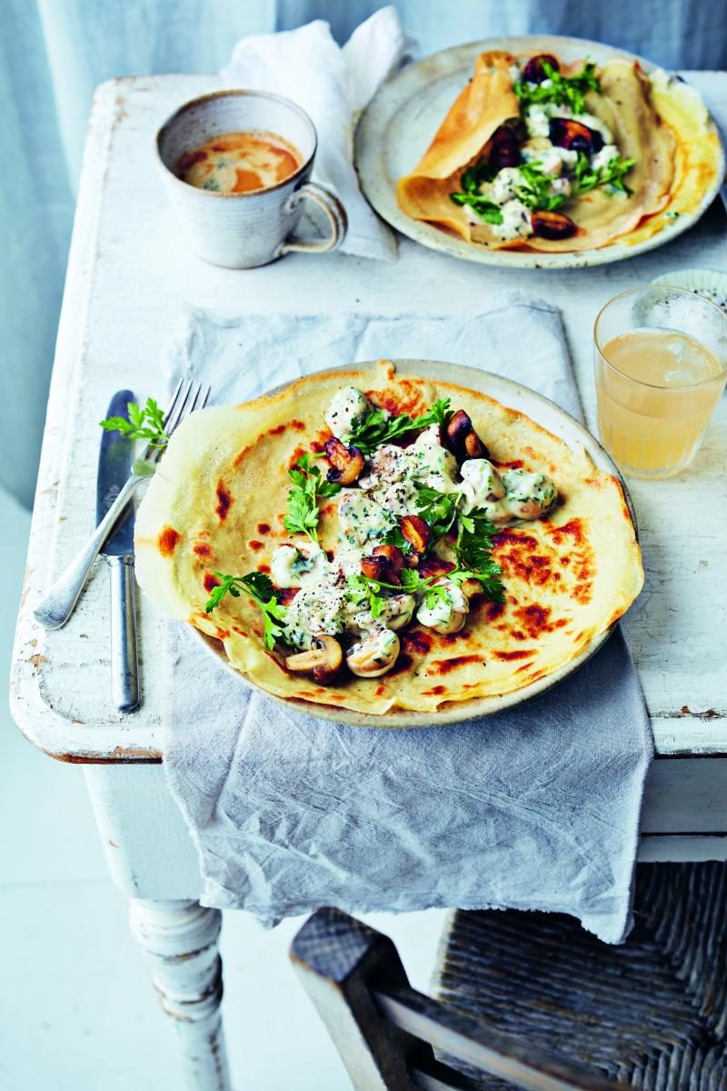 Vegan savoury pancakes with garlicky mushrooms on a rustic table on a neutral background