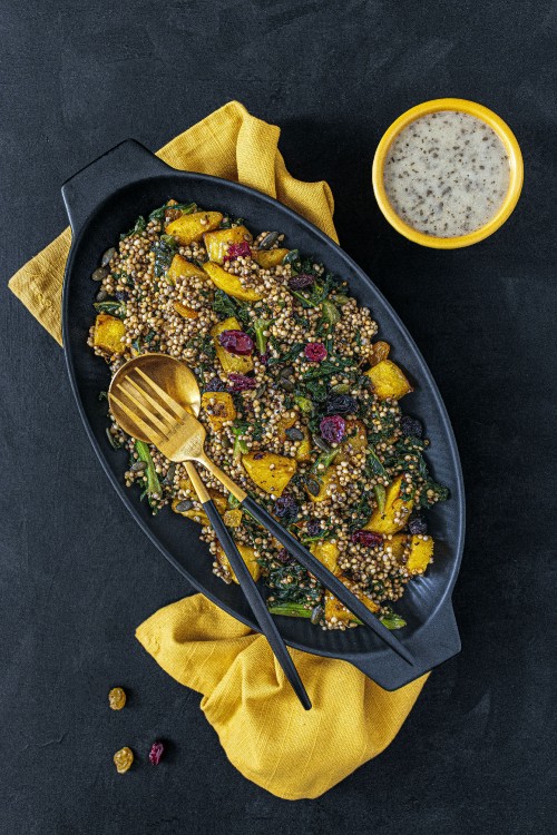 millet squash warm salad served in a bowl with knife and fork